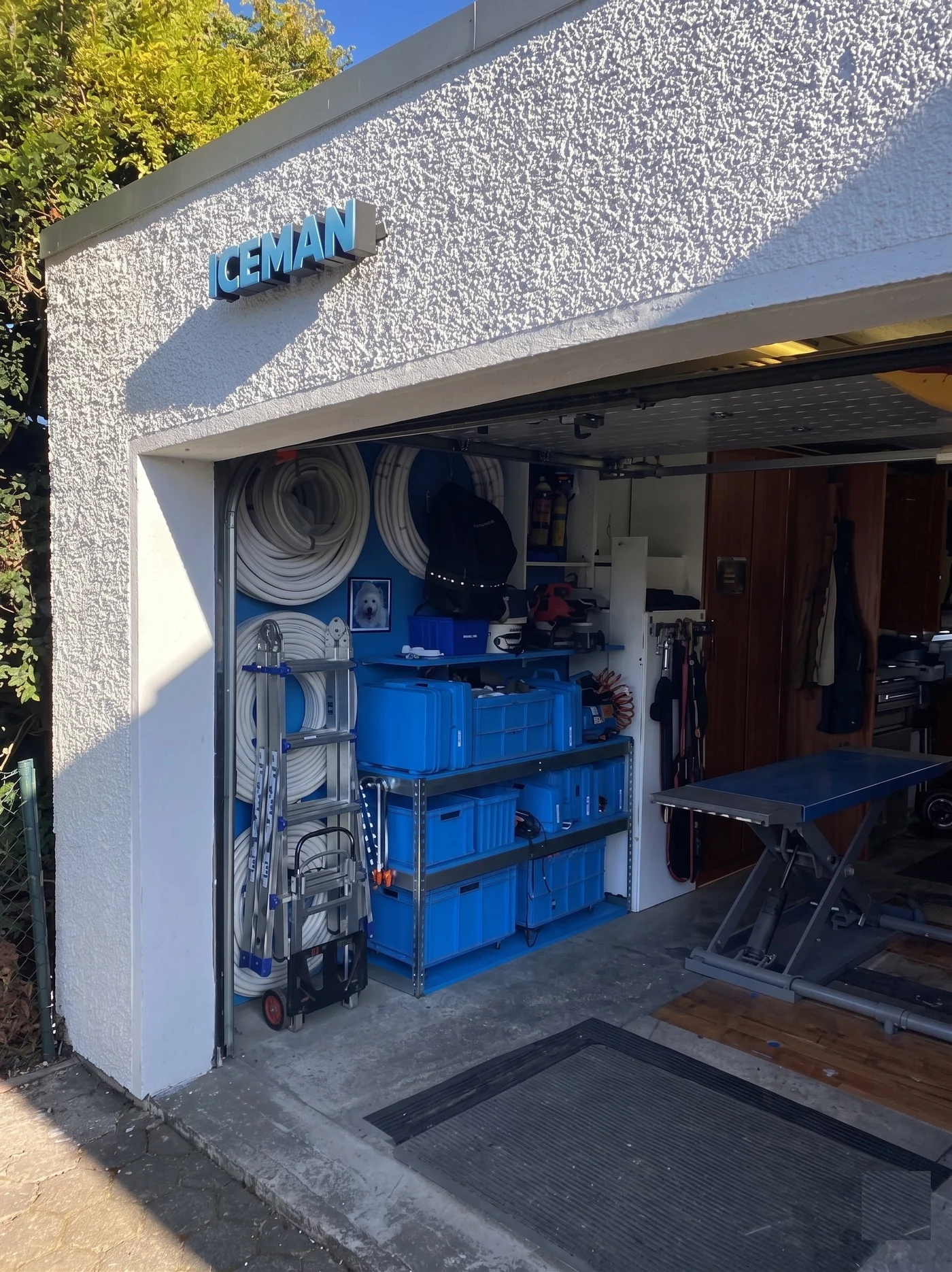 Firmensitz von ICEMAN mit beleuchtetem ICEMAN-Schriftzug über dem offenen Lager – ordentlich sortierte Leitungen, Werkzeugkisten und Montageausrüstung